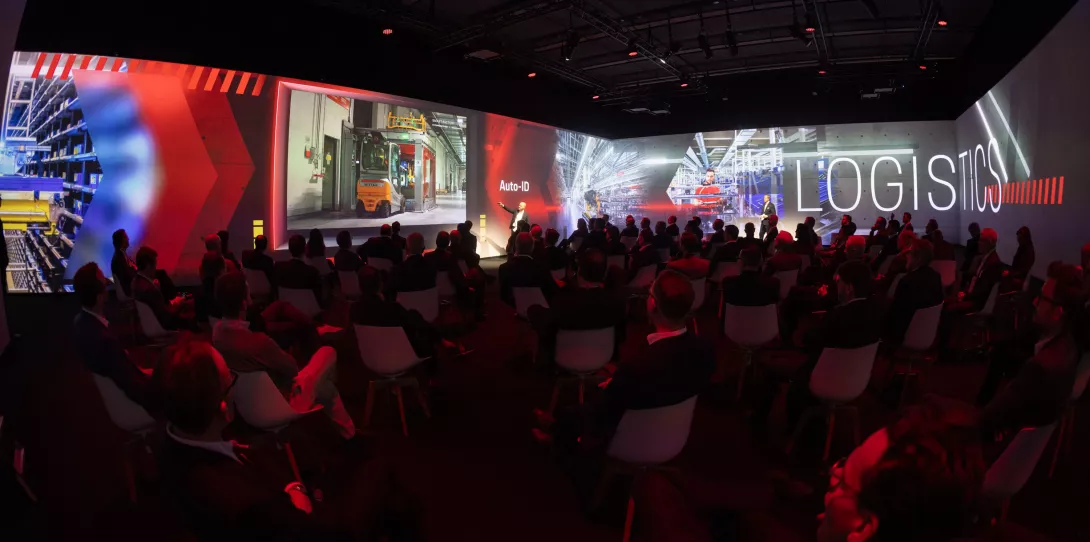 Porsche Consulting Global Operations Summit in Berlin People sitting in the immersive room with presentation