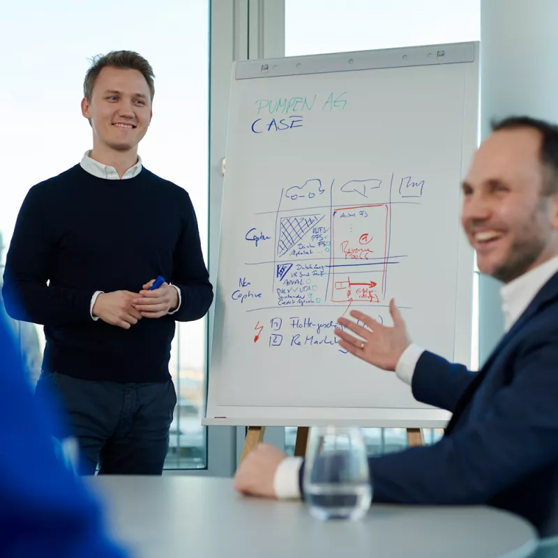 A young man presents the solution to a task on a flipchart