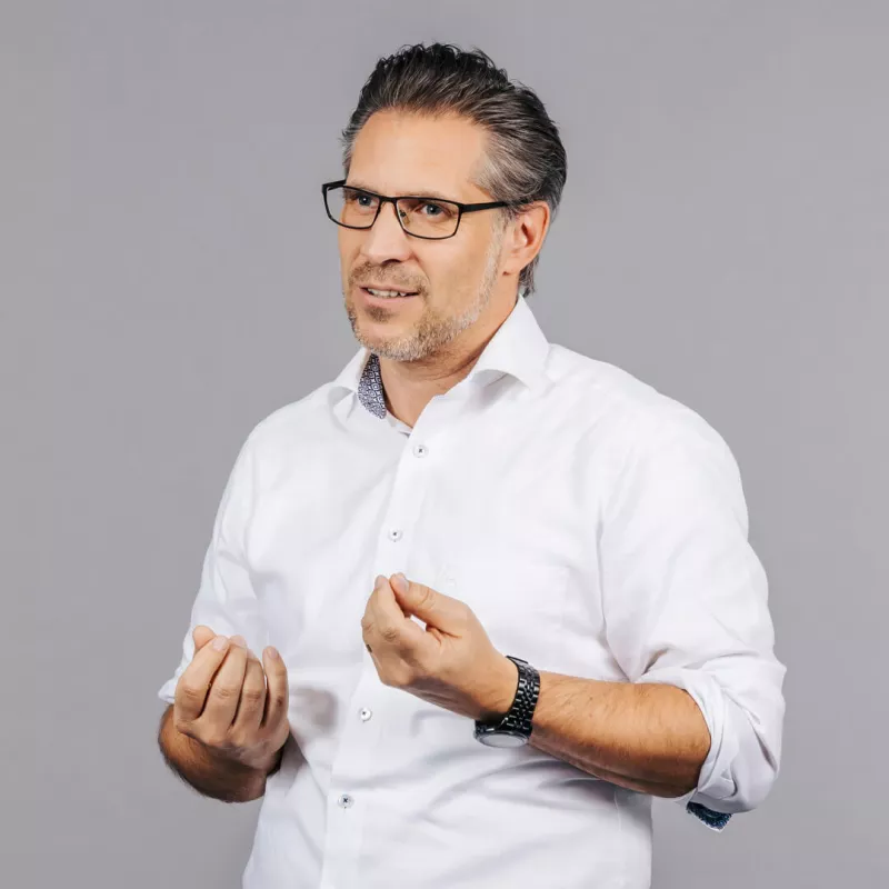 An employee of Porsche Consulting looks gesticulating into the camera