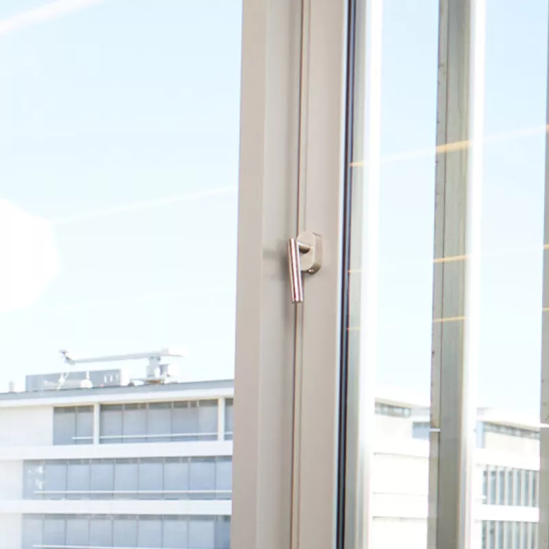 Mann in einem Anzug steht in einem Büro vor einer Fensterfront