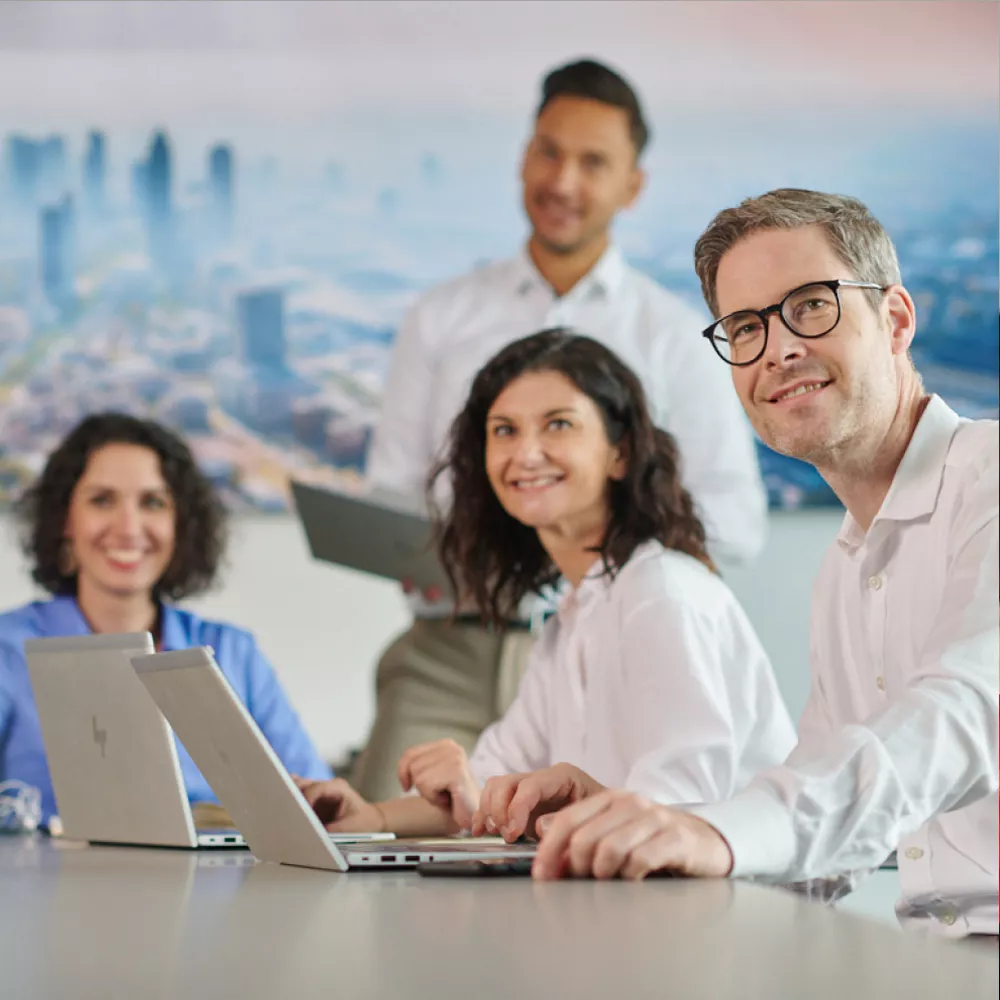 Several colleagues with laptops in one office