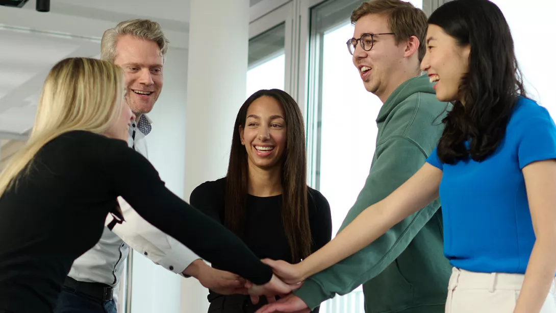 Female and male colleagues putting their hands together in an office