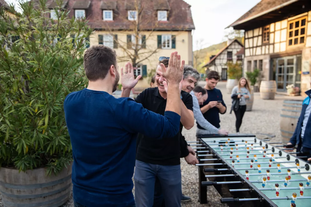 Zwei Kollegen klatschen sich beim Tischkicker ab