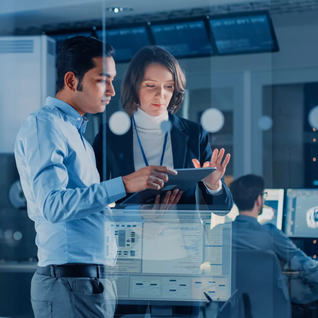 A woman and a man are looking at something on a tablet in an office