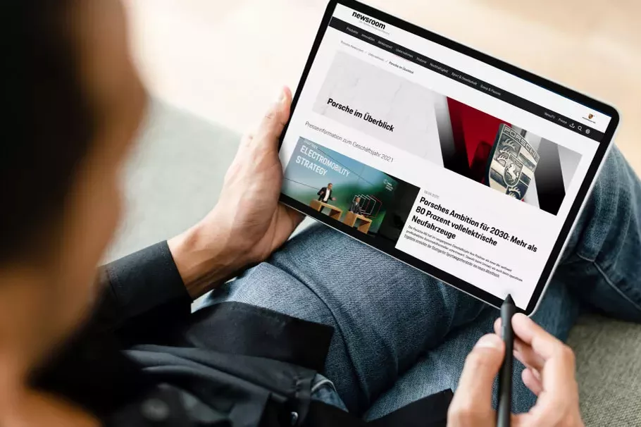 Man with laptop with Porsche Consulting website newsroom on his lap 
