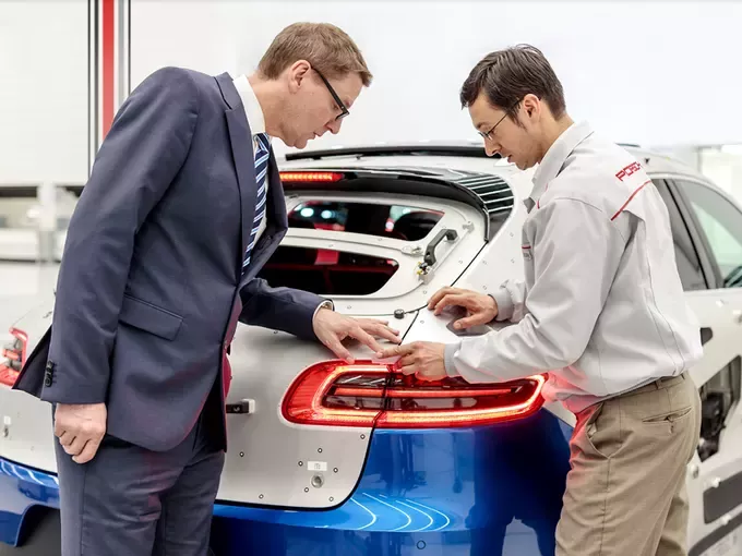 porsche factory worker shows work progress to business man