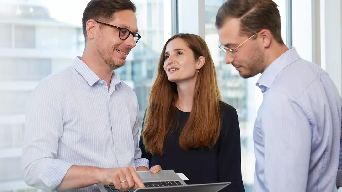 Two consultants and a female consultant in business outfits talk to each other