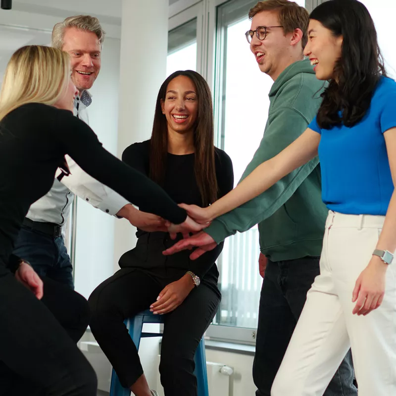 Female and male colleagues putting their hands together in an office