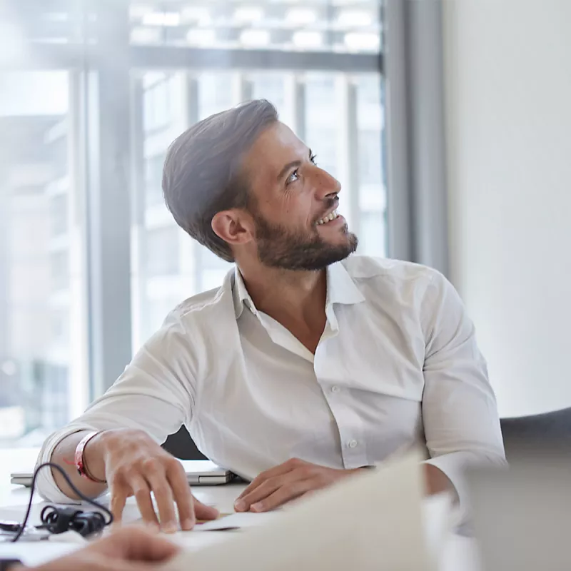 A consultant sitting at a table looks up and smiles
