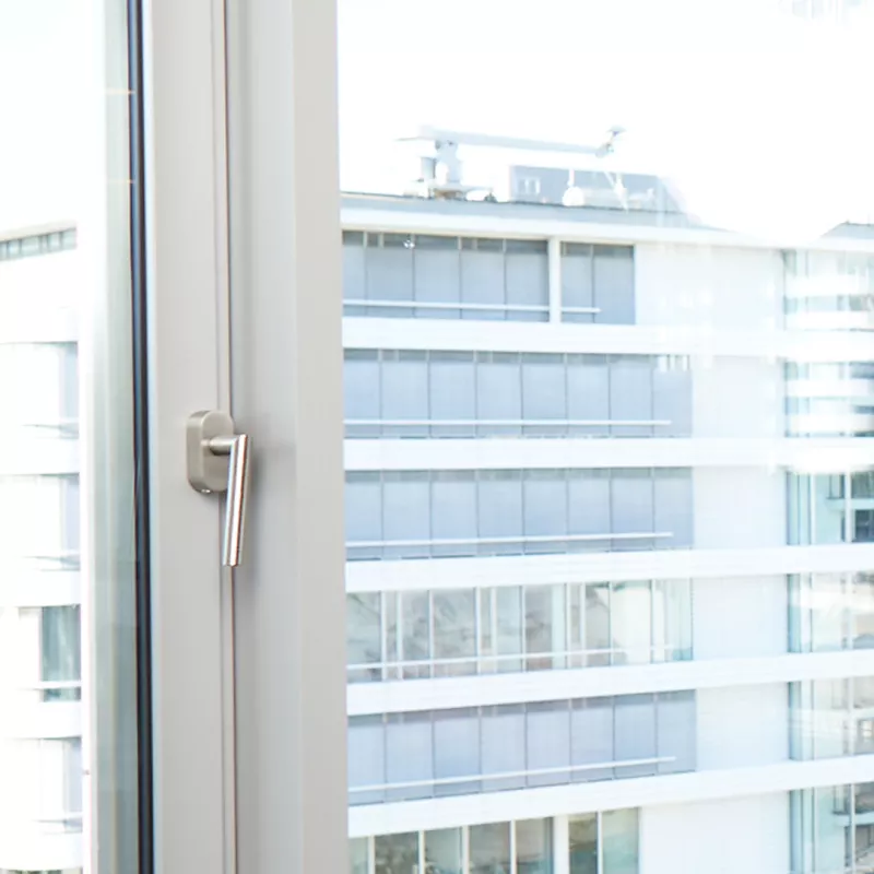 Man in a suit stands in front of a window in an office
