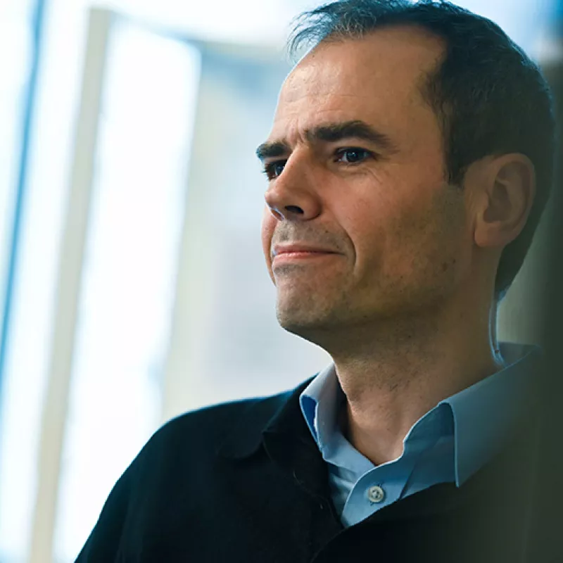 Picture of a man with light blue shirt and dark blue jumper